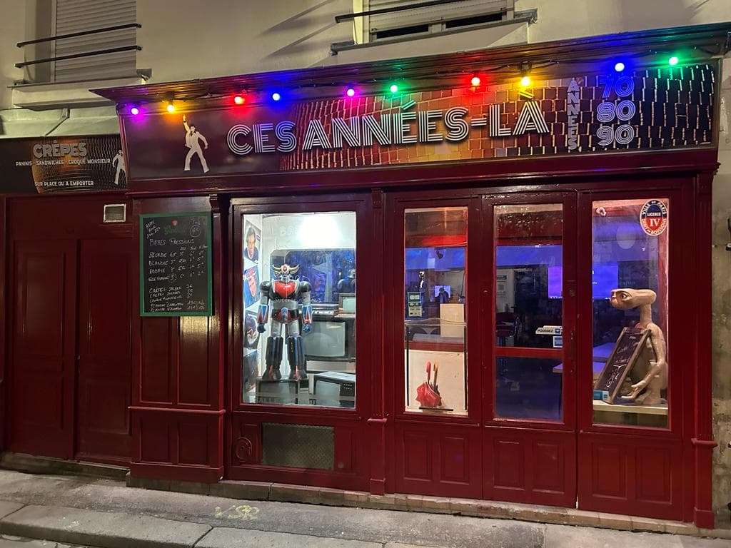 La devanture rouge de Ces Années Là, rue Laplace, sous sa guirlande d’ampoules de couleur : l’enseigne « 70 80 90 », Goldorak et E.T. en vitrine